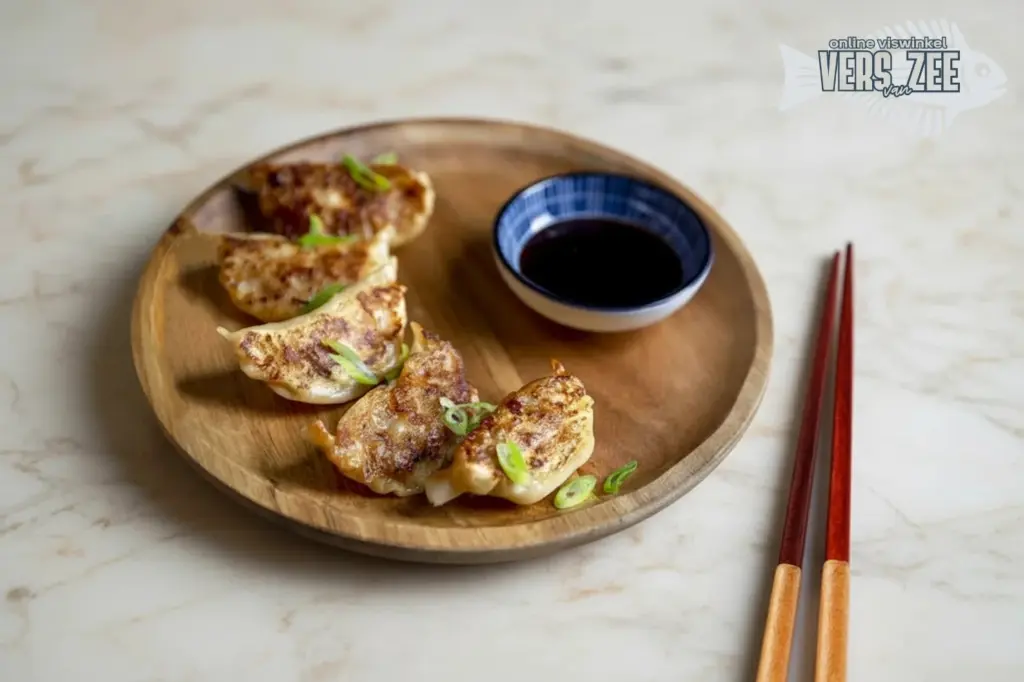 Vier gebakken gyoza dumplings met bosui op een rond houten bord, geserveerd met sojasaus en eetstokjes op een lichte marmeren ondergrond.